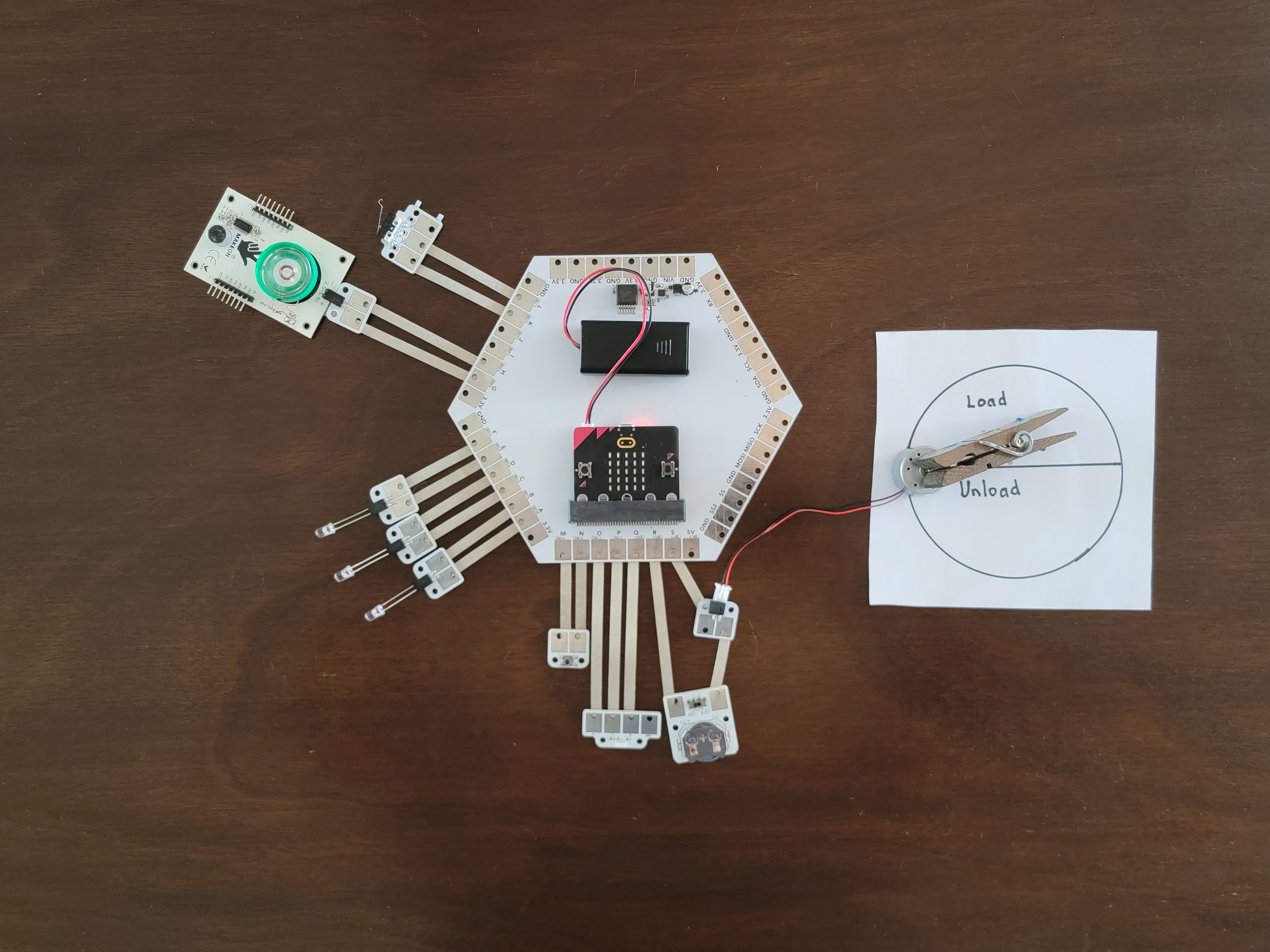 A microcontroller is connected to LEDs, multiple buttons and switches, and a motor.