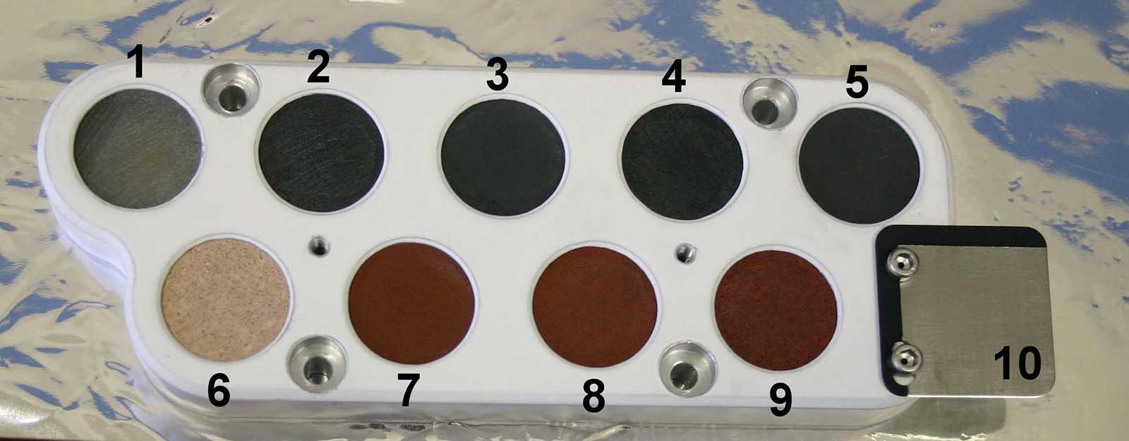 Small cyclindrical samples varying in color from shades of green on the top row to shades of red on the bottom row are shown in an up close image of the Curiosity rover's calibration target.