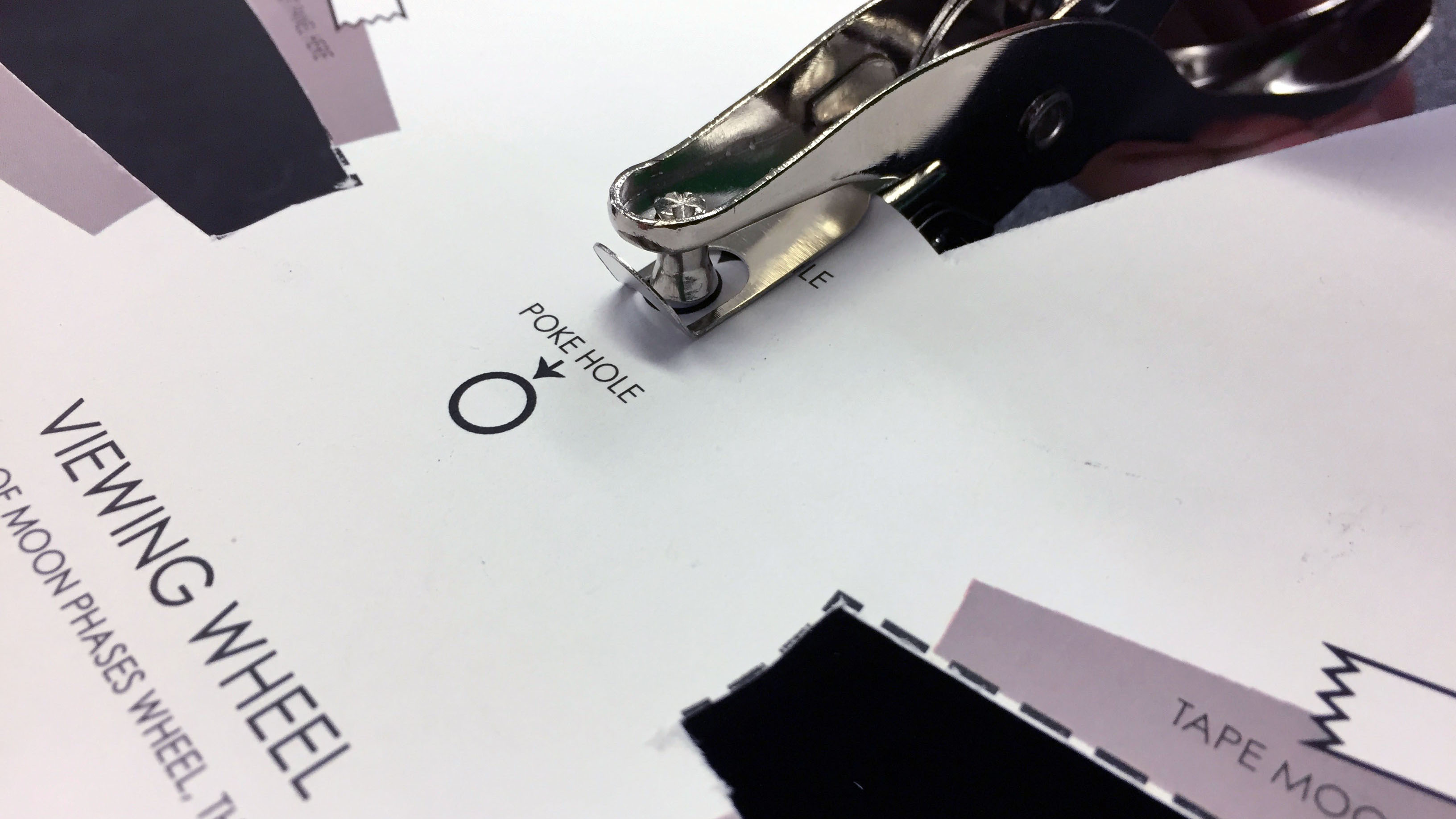 Using a hole punch to create a hole where it says View from space on the Viewing Wheel.