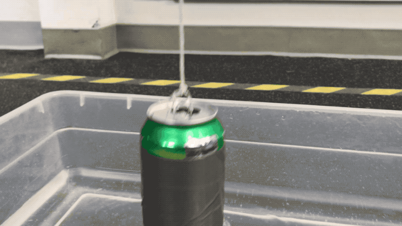 A can with angled holes is pulled out of the water tub suspended by a string. As water flows out of the holes, the can spins counter clockwise. Once the water has finished flowing out of the holes, the can spins back the other way.