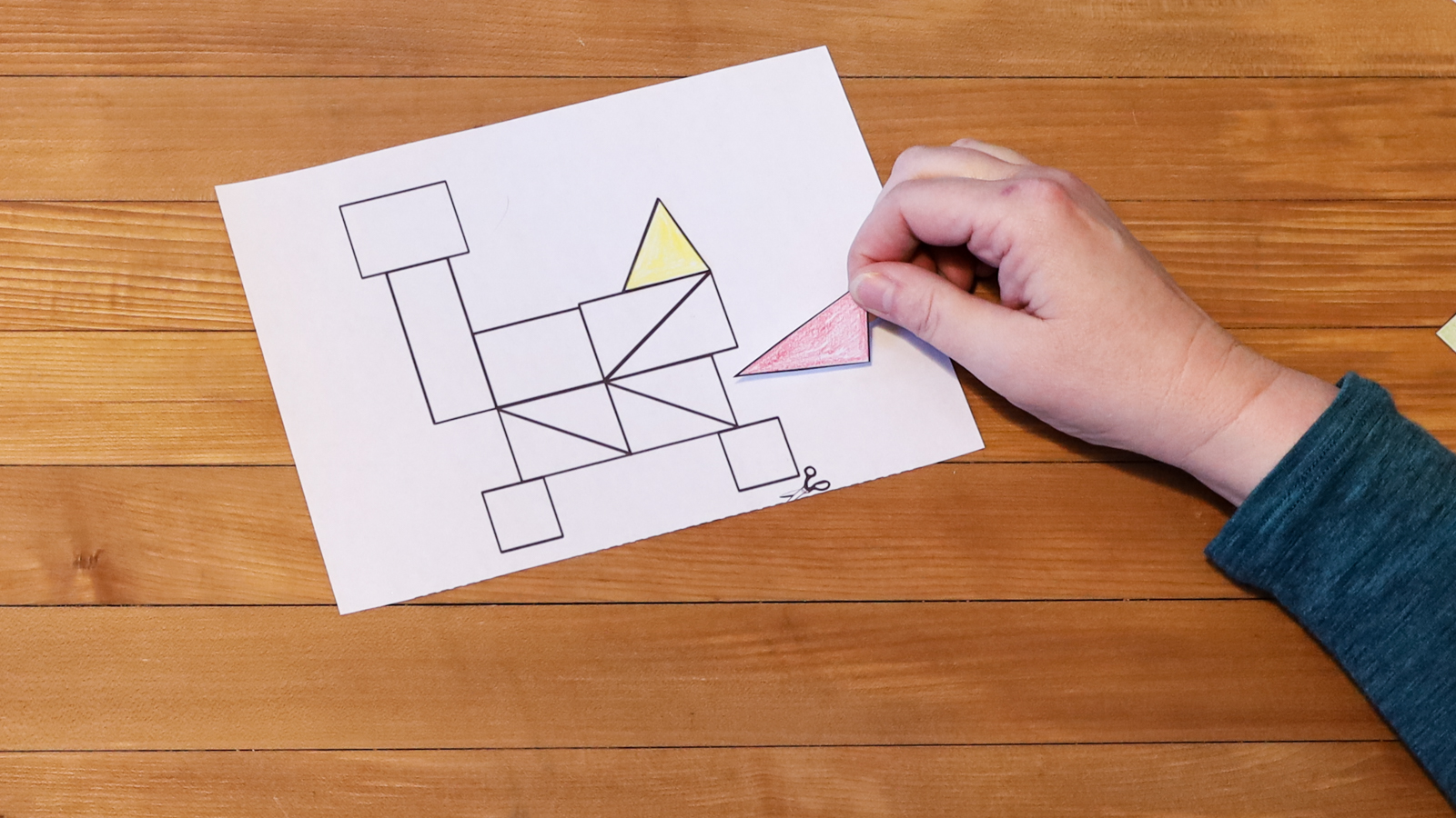 A person puts a shape onto the tangram rover outline.