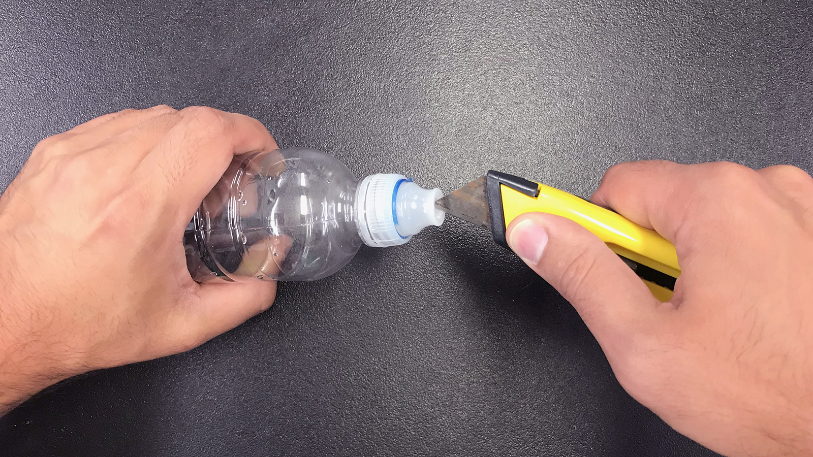 cutting a hole into the lid of the water bottle