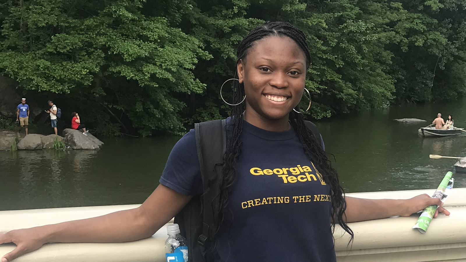 Breanna Ivey wears a Georgia Tech T-Shirt and poses in front of a river with her arms outstretched on concrete railing.