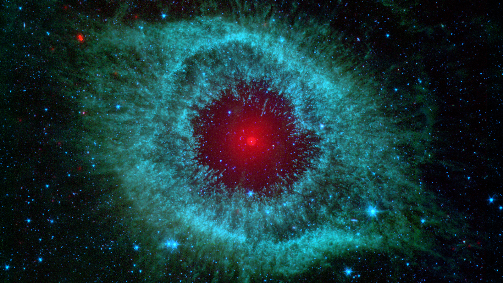 A giant red star is surrounded by an almond-shaped burst of green stellar dust, appearing like the pupil and iris of a human eye.