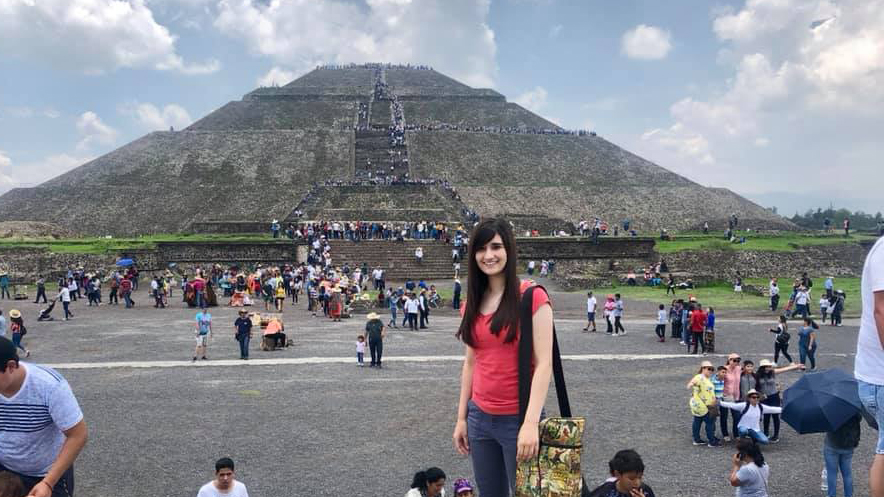 Izzie Torres poses in front of an ancient pyramid.