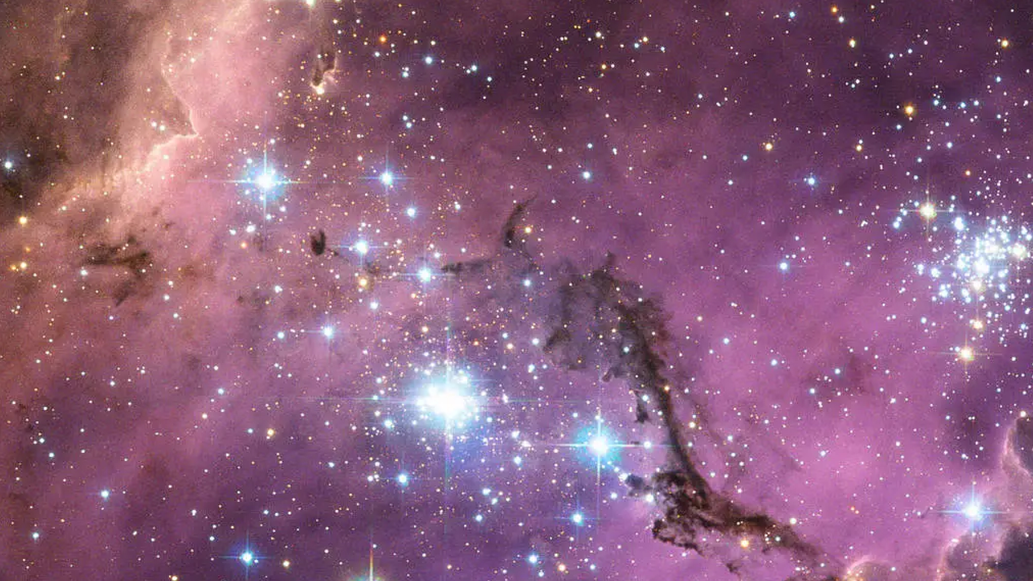 Thick clouds of purple and pastel pink cover a speckled field of stars with clusters of large and especially bright blue and yellow stars glowing through the clouds.