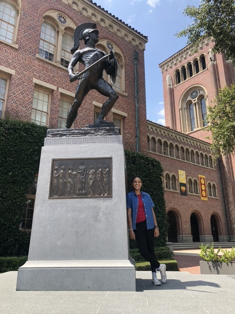 Deo leans against the base of a statue of USC's Trojan mascot.