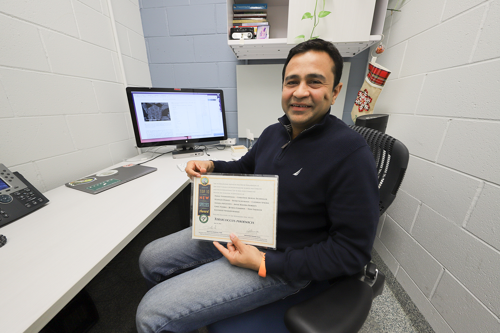 Vaishampayan sits in his stark white office holding a laminated award.