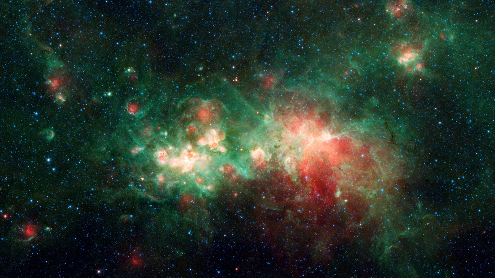Swirls of green and red dotted by blue stars make up this infrared view of nebula W51