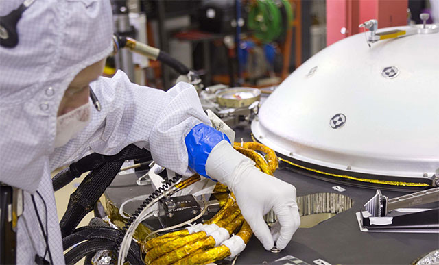 A spacecraft specialist affixes onto the spacecraft deck one of the dime-size chips