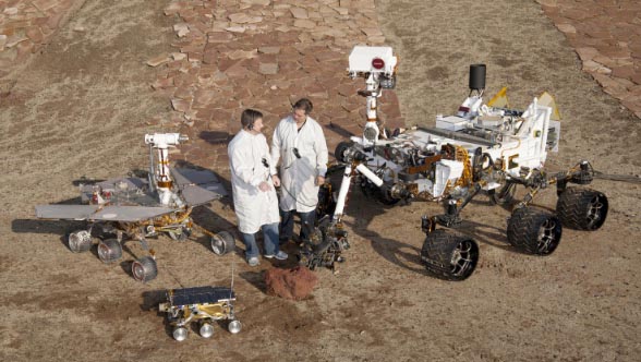 Past and present mars rover models displayed next to two scientists