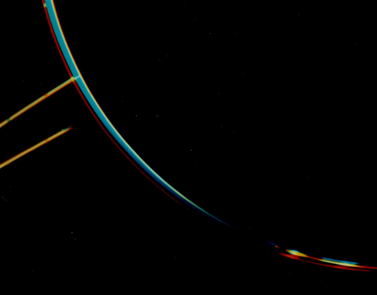 Jupiter's faint ring system is shown in this color composite as two light orange lines protruding from the left toward Jupiter's limb. This image was taken by NASA's Voyager 2 spacecraft.